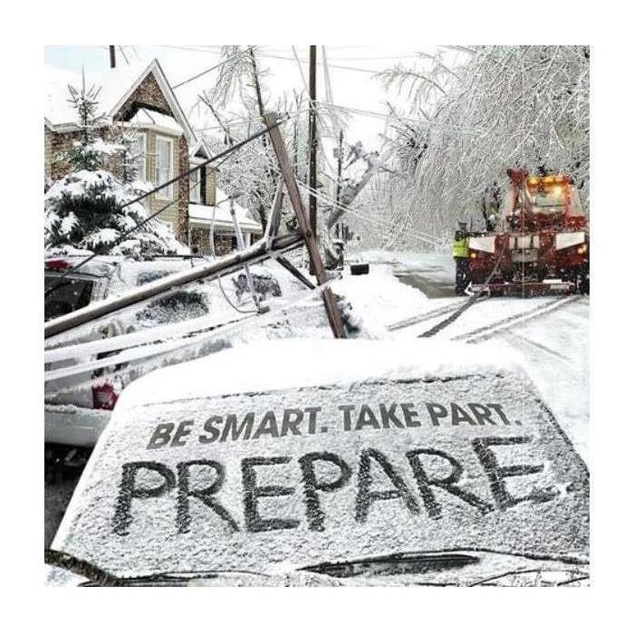 Tow truck towing a car out under a fallen light post from a snow storm, a windshield reads "be smart, take part, be prepared"