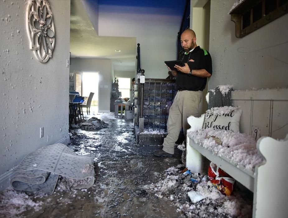 Servpro professional inspecting and documenting damage in a home after a storm 